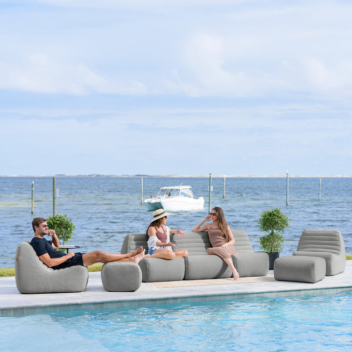 People relaxing on outdoor furniture by a pool with a scenic ocean view. #color_port-gray-outdoor-performance-linen