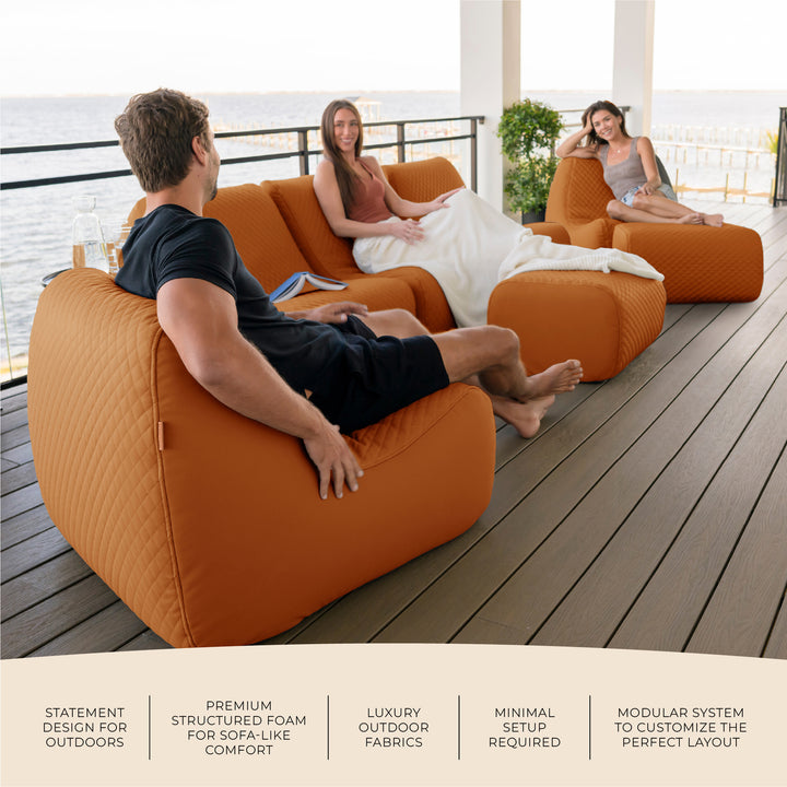 People sitting on orange outdoor furniture on a wooden deck. #color_honey-sand-outdoor-vegan-leather