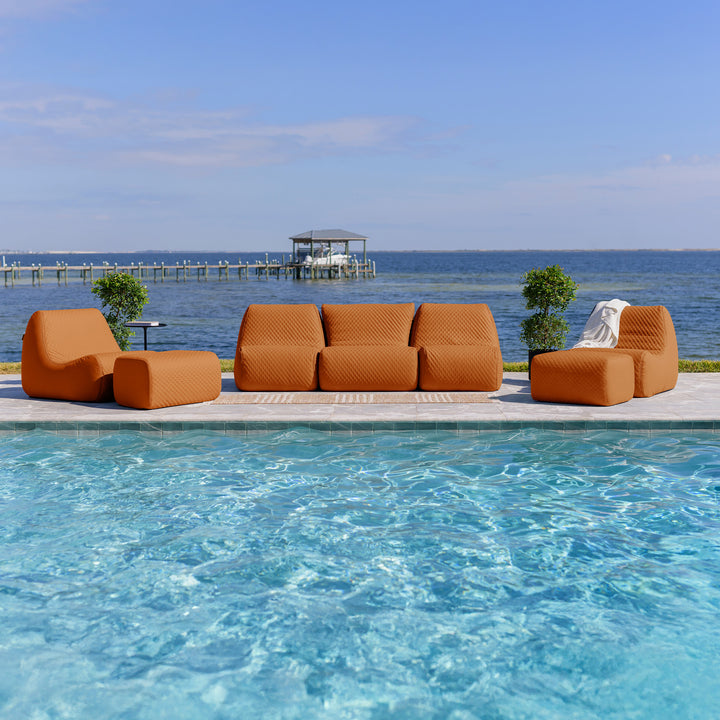 Orange outdoor furniture set by a pool with a scenic background #color_honey-sand-outdoor-vegan-leather