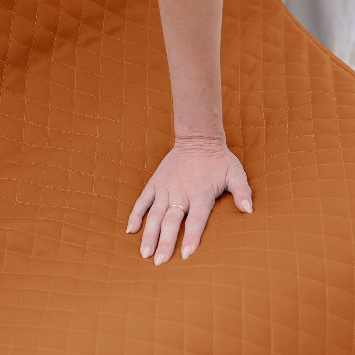 Hand on a brown quilted surface #color_honey-sand-outdoor-vegan-leather