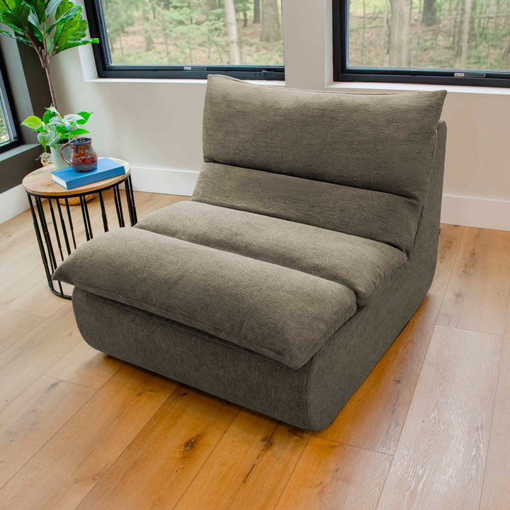 Gray floor pillow on a wooden floor with a small round table and plants in the background. 