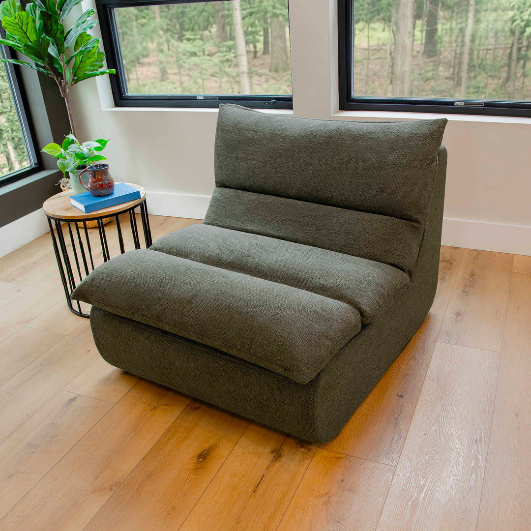Green floor pillow in a room with windows and a small table. 