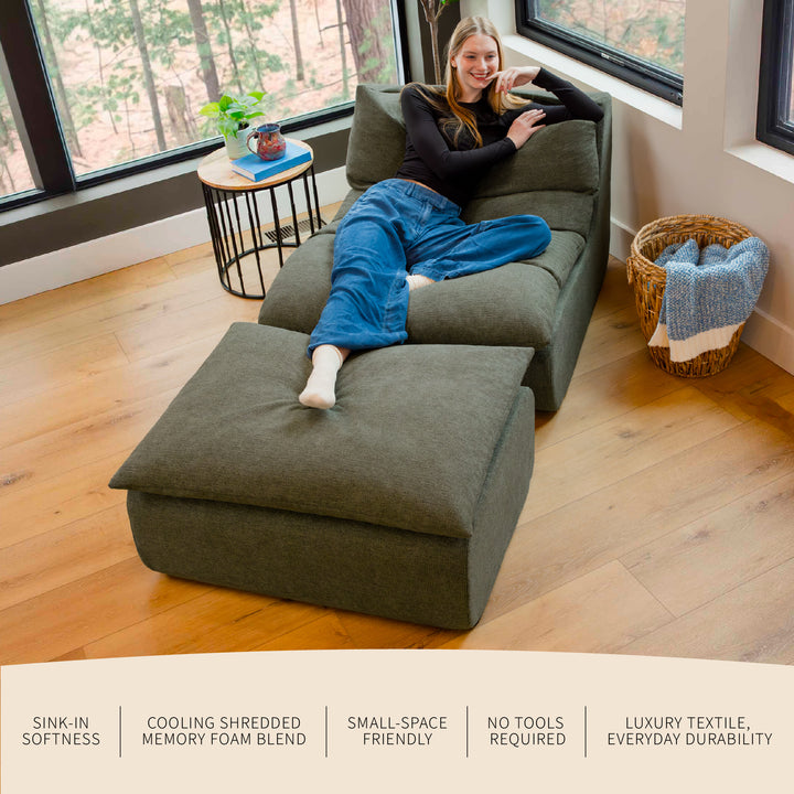 Person sitting on a large green ottoman in a room with large windows. 