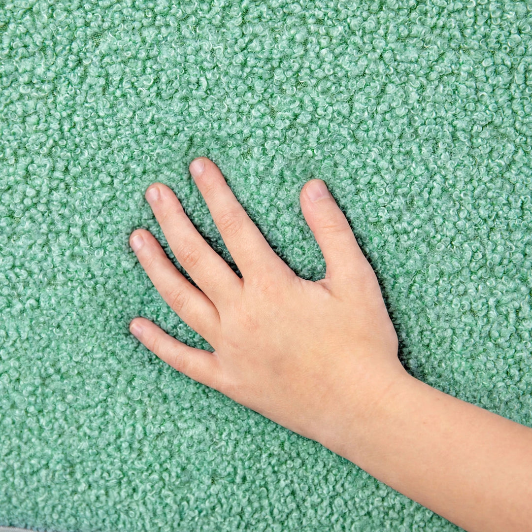 A close-up of a textured green plush carpet with a child&