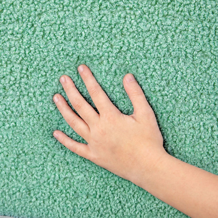 A close-up of a textured green plush carpet with a child&