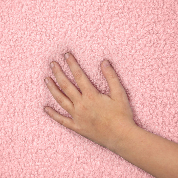 A close-up of a hand resting on a soft, textured pink fleece or sherpa fabric surface. 