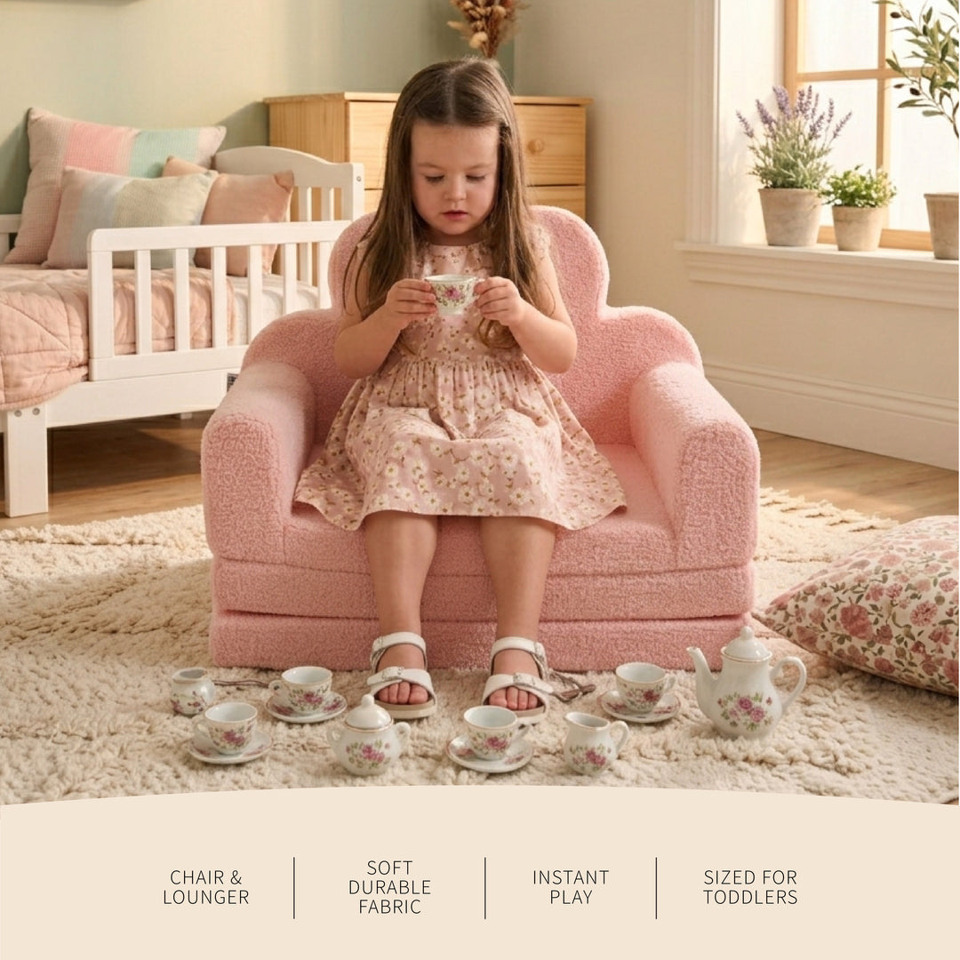 A young girl sits in a small pink boucle chair lounge in a cozy bedroom setting, holding a teacup from a matching floral tea set arranged on the floor. The scene includes text overlays at the bottom describing the chair and lounge features. 