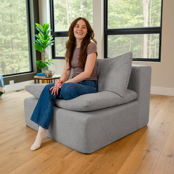 Woman sitting on a gray pillow-top chair 