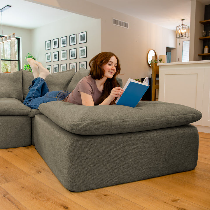Woman laying on a couch with book on an ottoman 