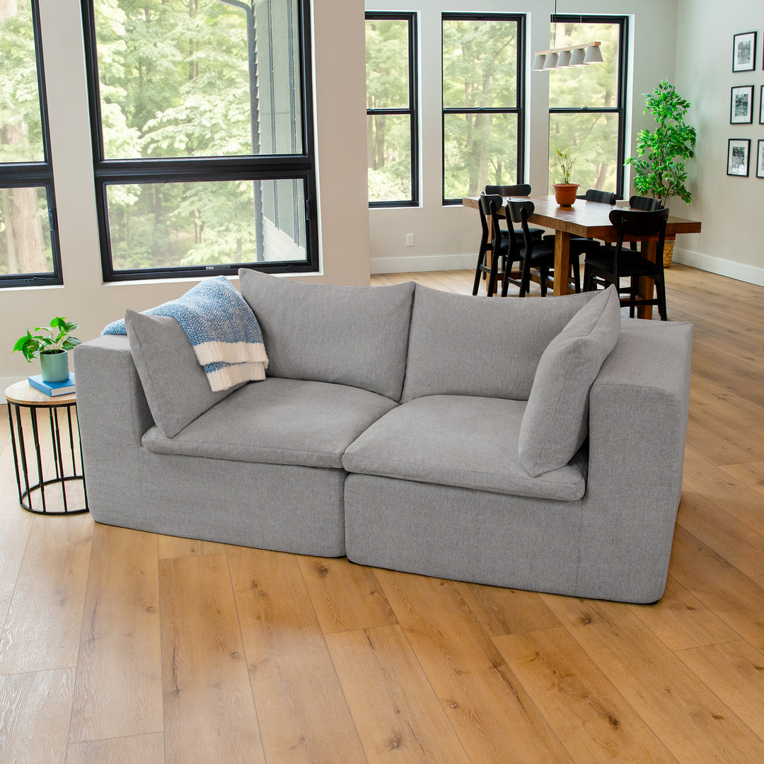 Gray sofa in a living room with large windows and a dining area. #color_cottage-gray-terra-knit
