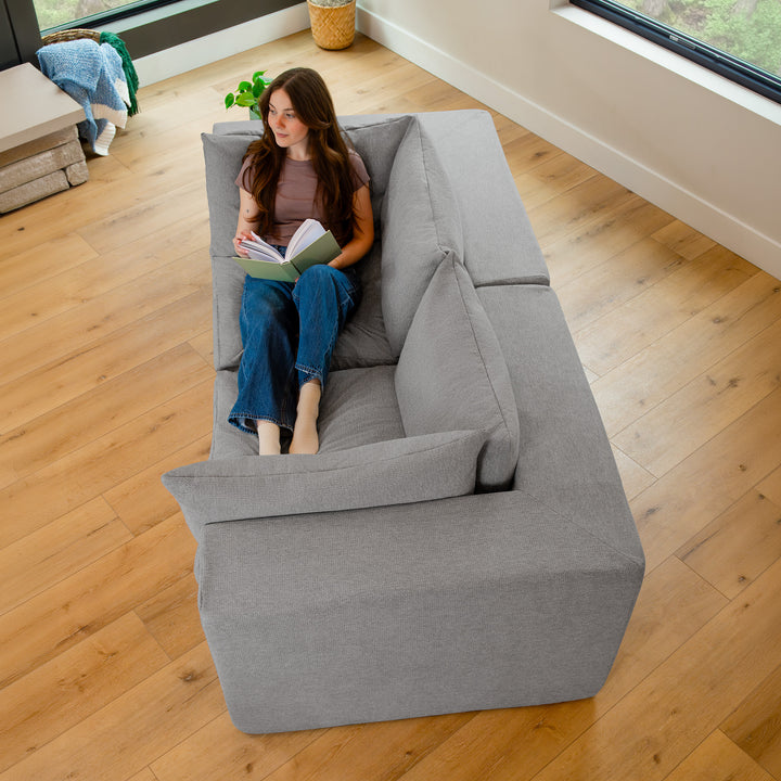 Woman reading a book on a loveseat, image shot from above looking down 