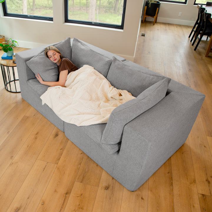 Woman laying on a loveseat with a blanket on in the living room 