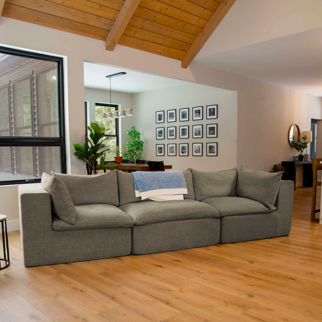 Gray sectional sofa in a living room with wooden floor and wall art. #color_misty-gray-terra-knit