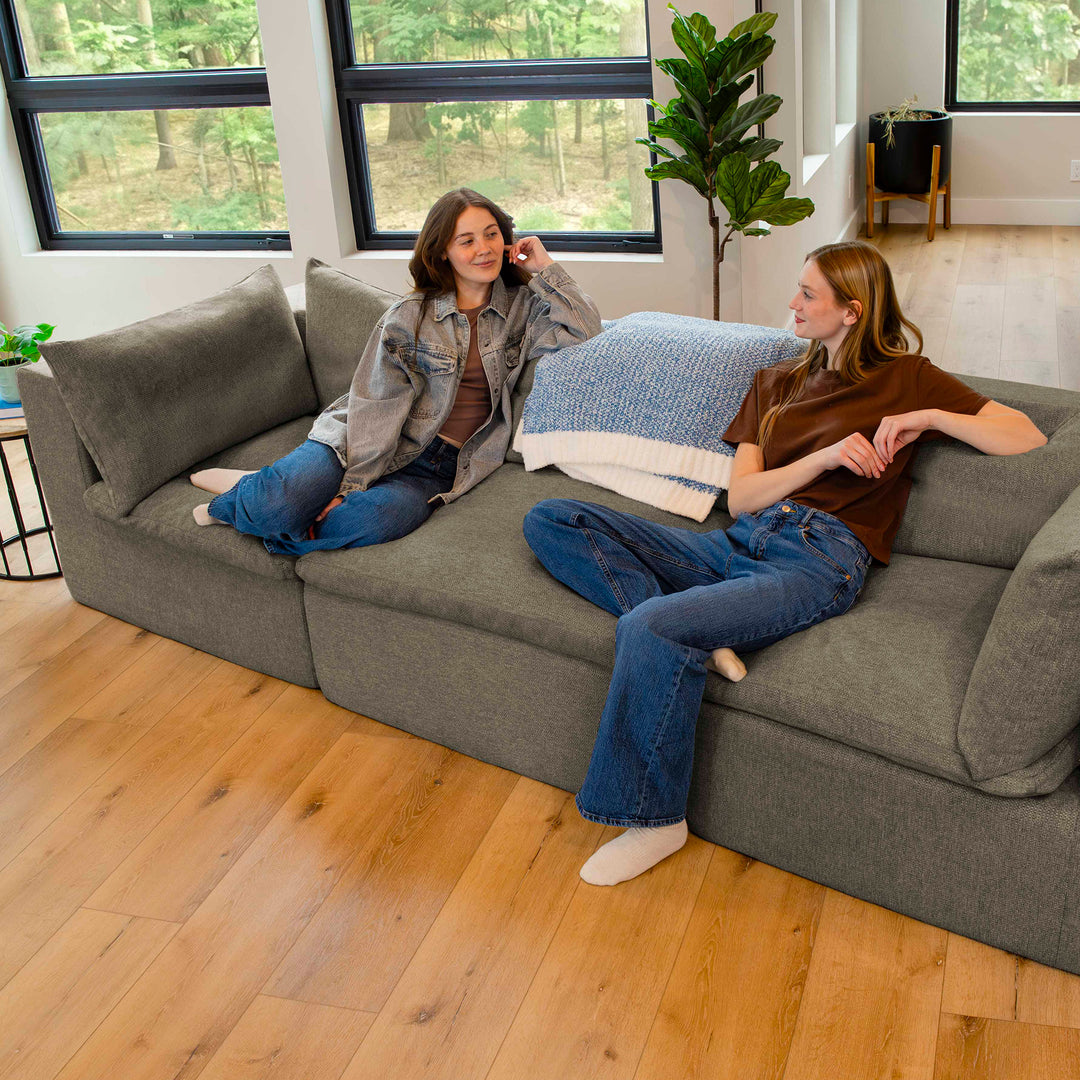 Two people sitting on a gray sectional sofa in a modern living room. 