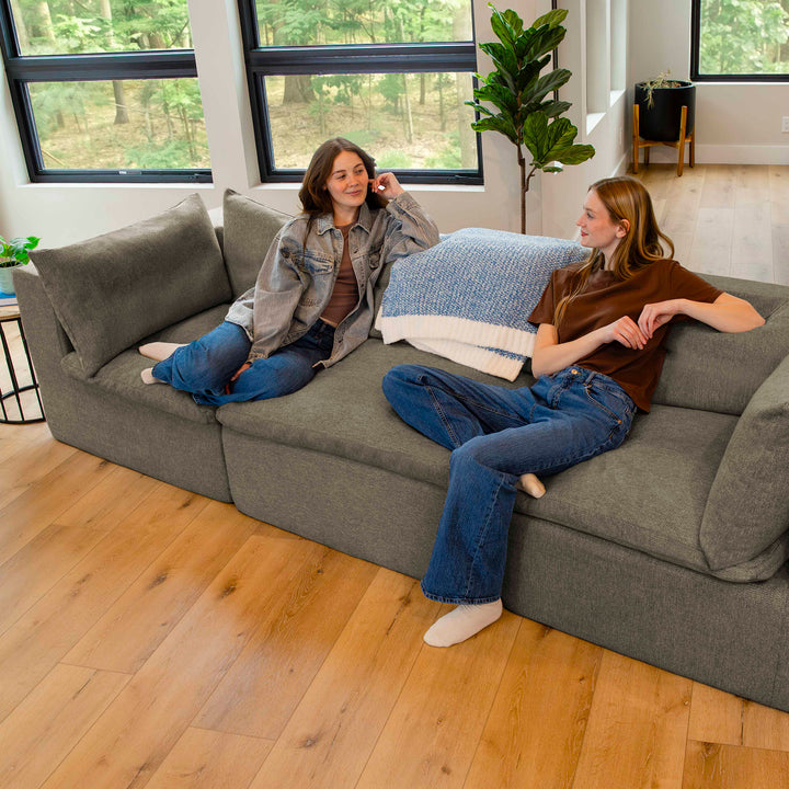 Two people sitting on a gray sectional sofa in a modern living room. 