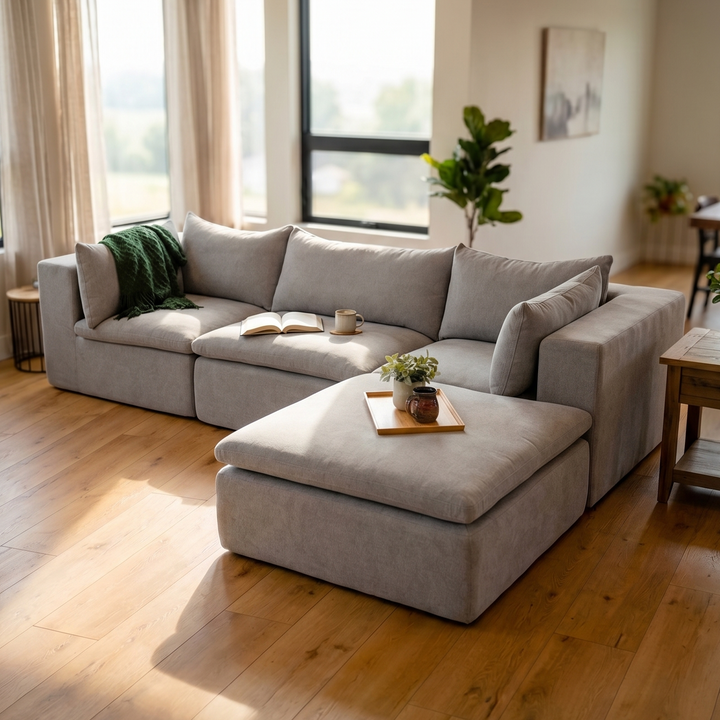 Gray sectional sofa in a living room with wooden floor and large windows. 