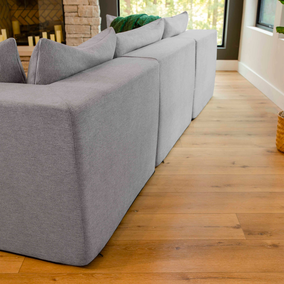 Gray sofa in a living room with wooden floor and windows. 