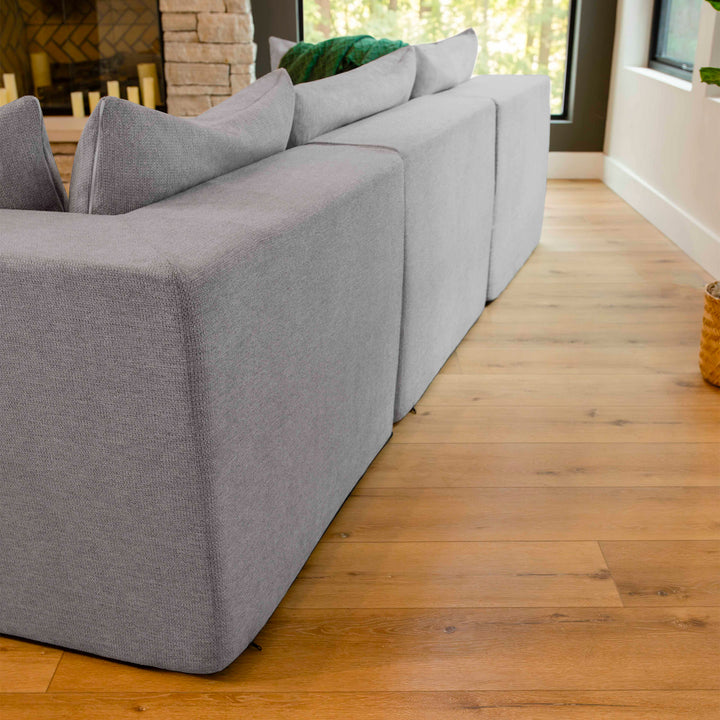 Gray sofa in a living room with wooden floor and windows. 