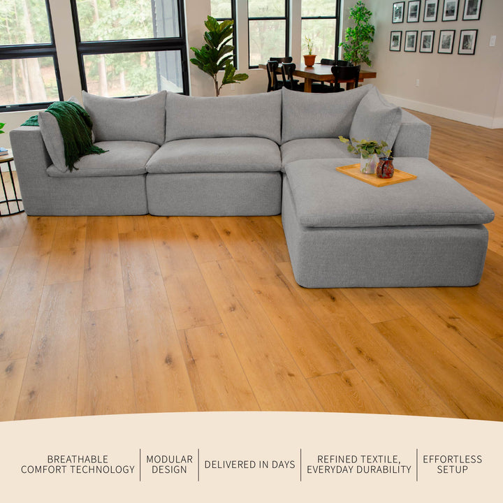 Gray sectional sofa in a living room with wooden floor and large windows. 