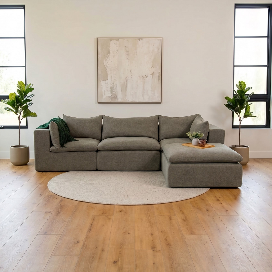 Gray sectional sofa in a modern living room with plants and artwork. 