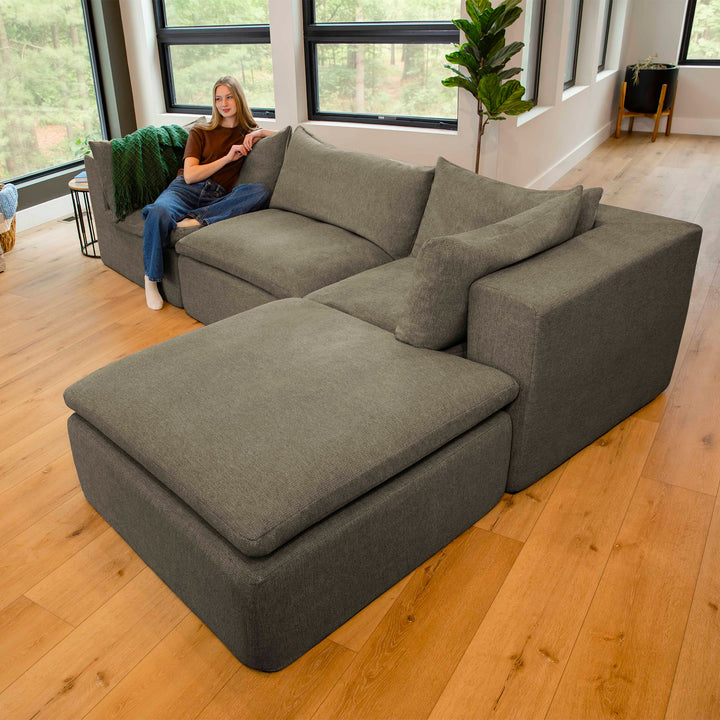 Gray sectional sofa in a living room with a person sitting on it. 