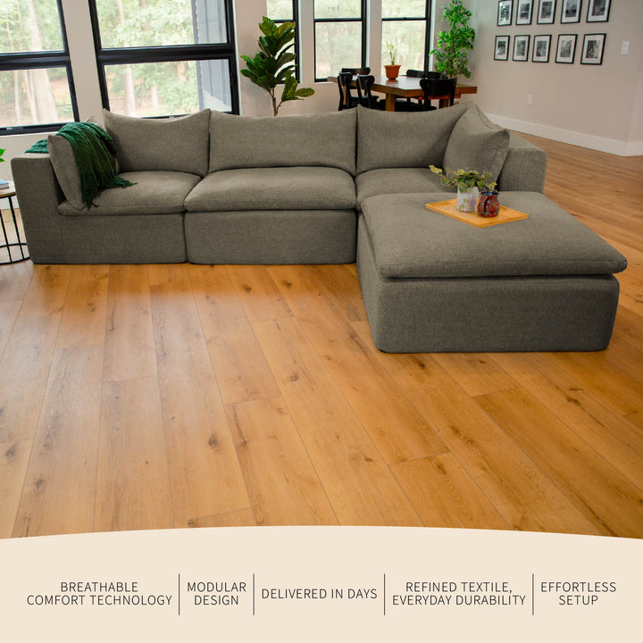 Gray sectional sofa in a living room with wooden floor and large windows. 