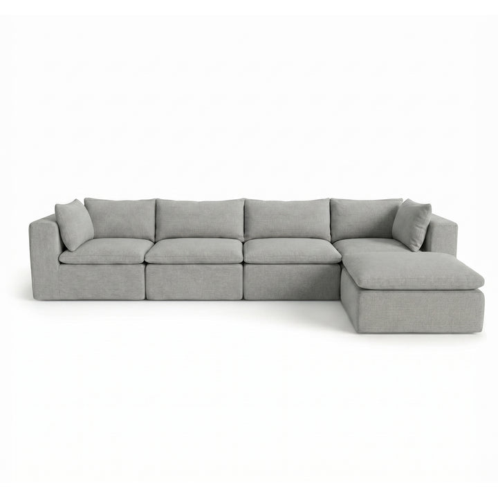 A light gray modular sectional sofa with a right-facing chaise lounge and matching throw pillows, shown against a plain white background. 