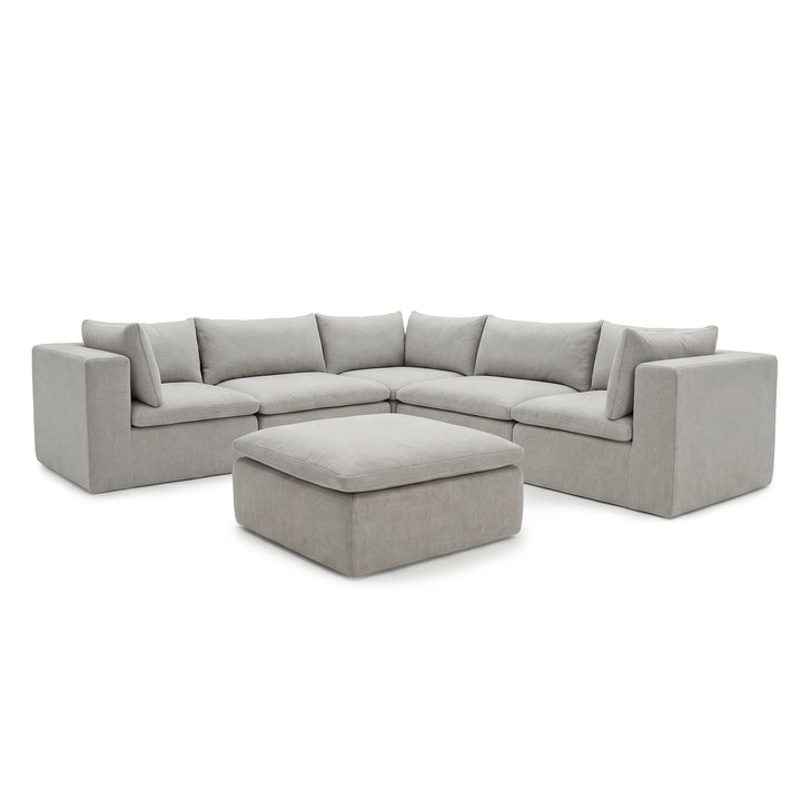 A light gray upholstered sectional sofa with matching square back cushions and a matching ottoman, shown on a plain white studio background. 