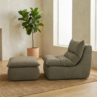 A modern lounge chair with a matching ottoman in a muted sage green fabric, styled in a minimalist room with a potted fiddle-leaf fig plant and a woven rug. #color_olive-green-terra-knit