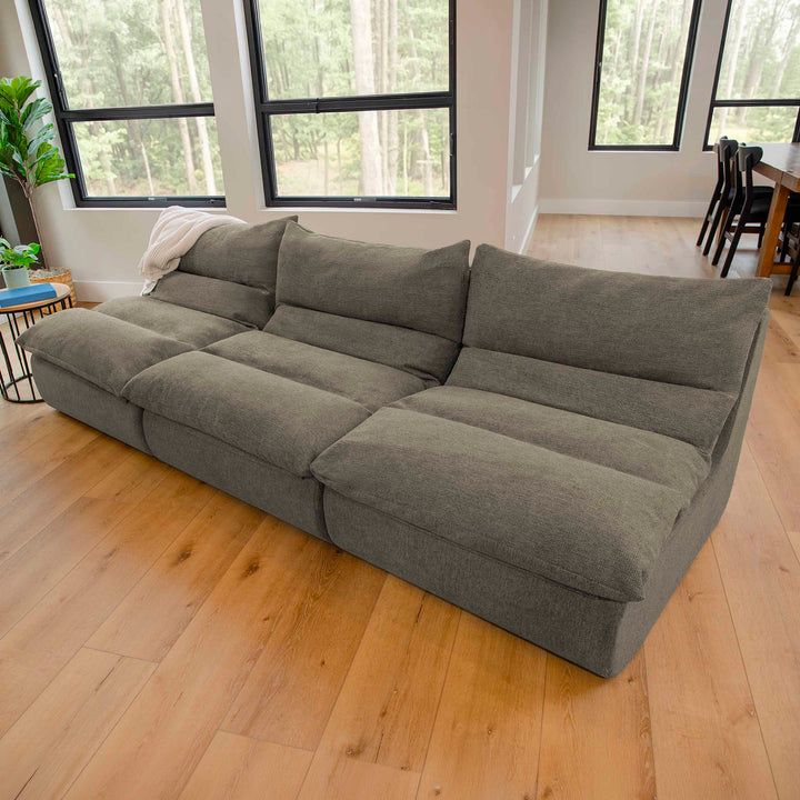 Gray sectional sofa in a room with large windows and wooden flooring 