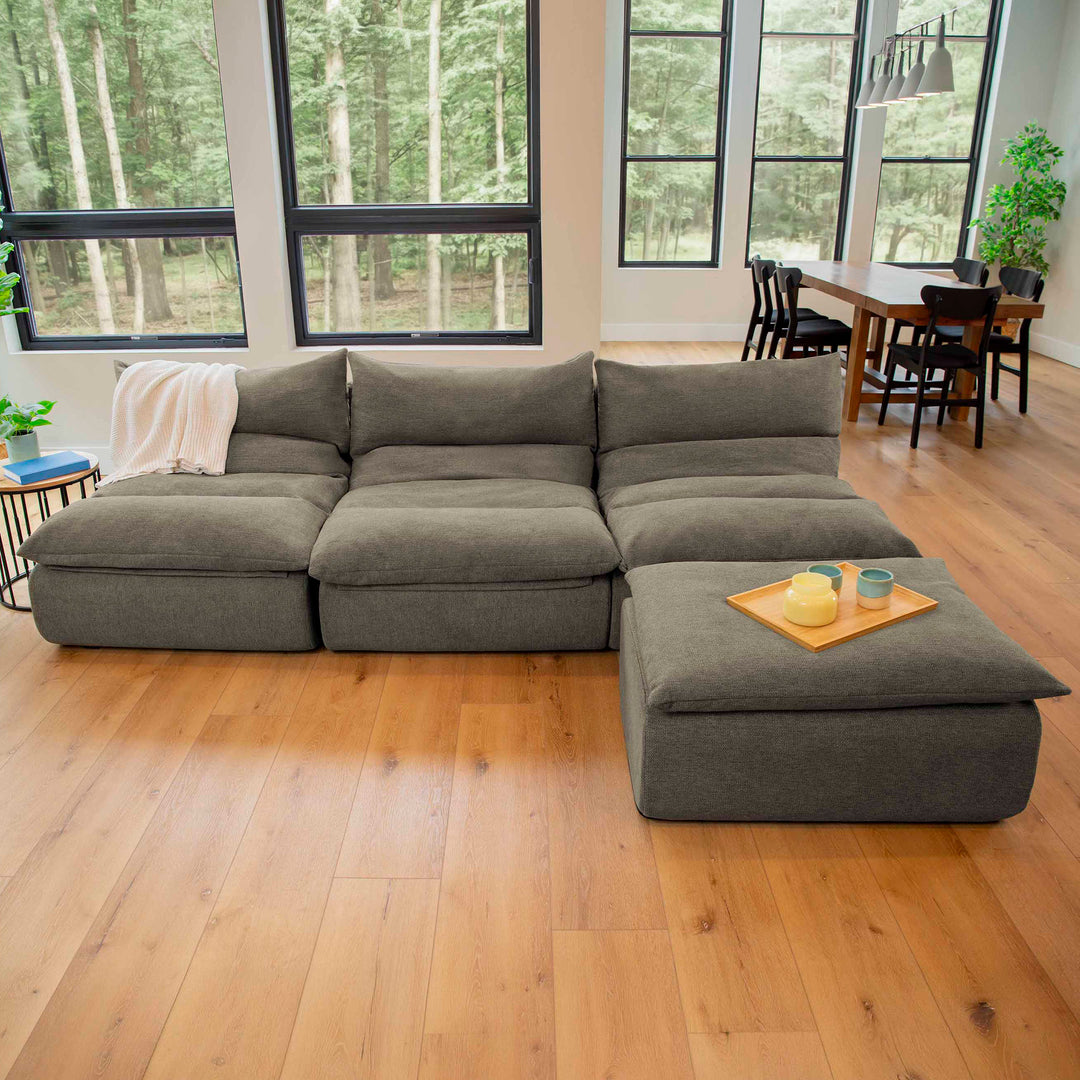 Gray sectional sofa in a room with large windows and a dining area. 