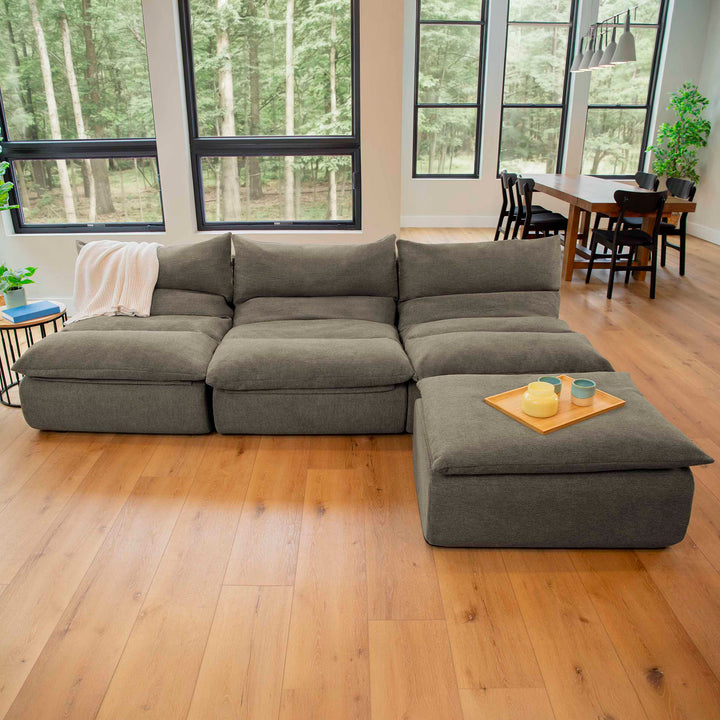 Gray sectional sofa in a room with large windows and a dining area. 
