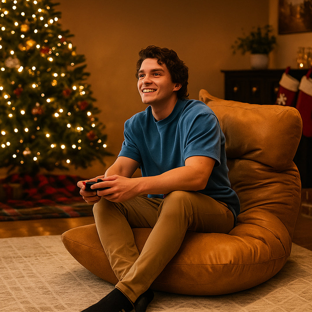 Person sitting on a brown bean bag chair holding a game controller in front of a Christmas tree. #color_rustic-tan