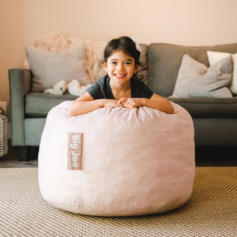 Young girl on Fuf small foam beanbag chair #color_desert-rose-plush
