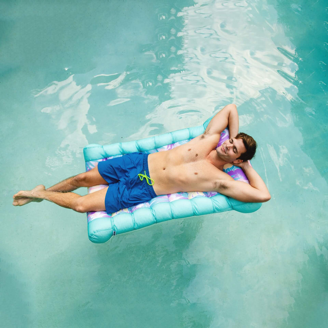 Man relaxing in pool on kona lounger #color_aqua-tropical-hibiscus